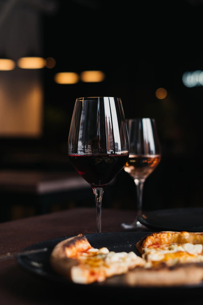 Glasses with red wine, white wine and pizza on dinner table