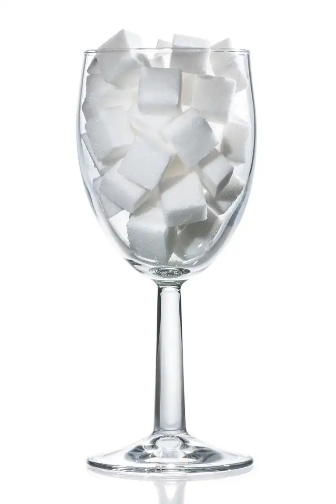 Wine glass filled with cubes of sugar on a white background