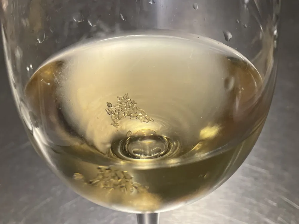 Tartaric acid crystals at the bottom of a glass of white wine