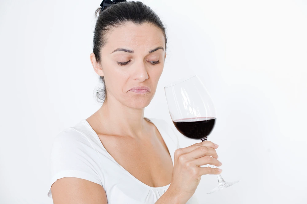 Woman examining wine that has gone bad