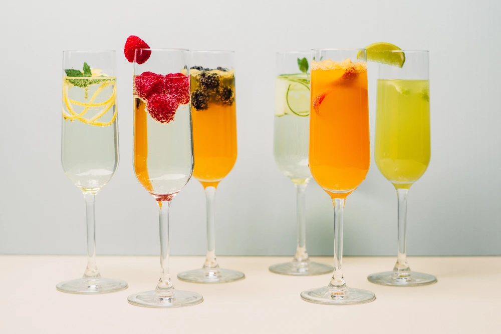 A range of champagne mimosas lined up on a white background
