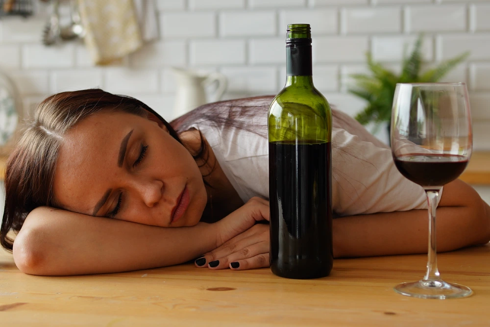 Woman sleeping on table after drinking red wine