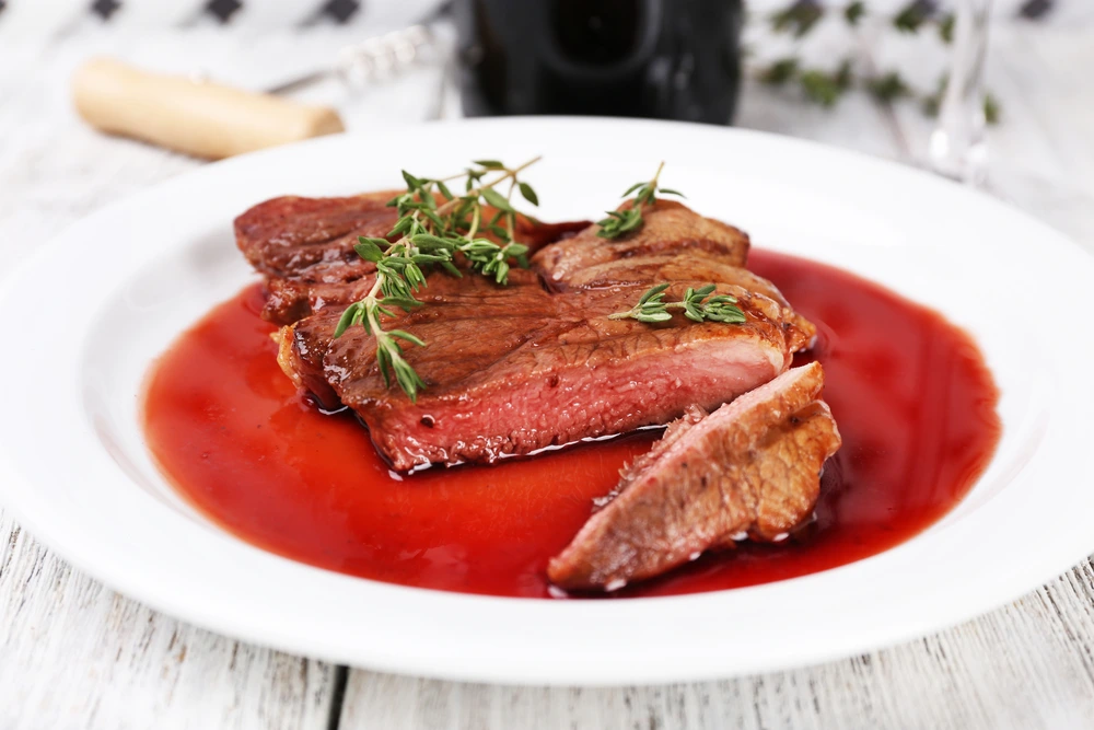 Steak with wine sauce on plate on a wooden table