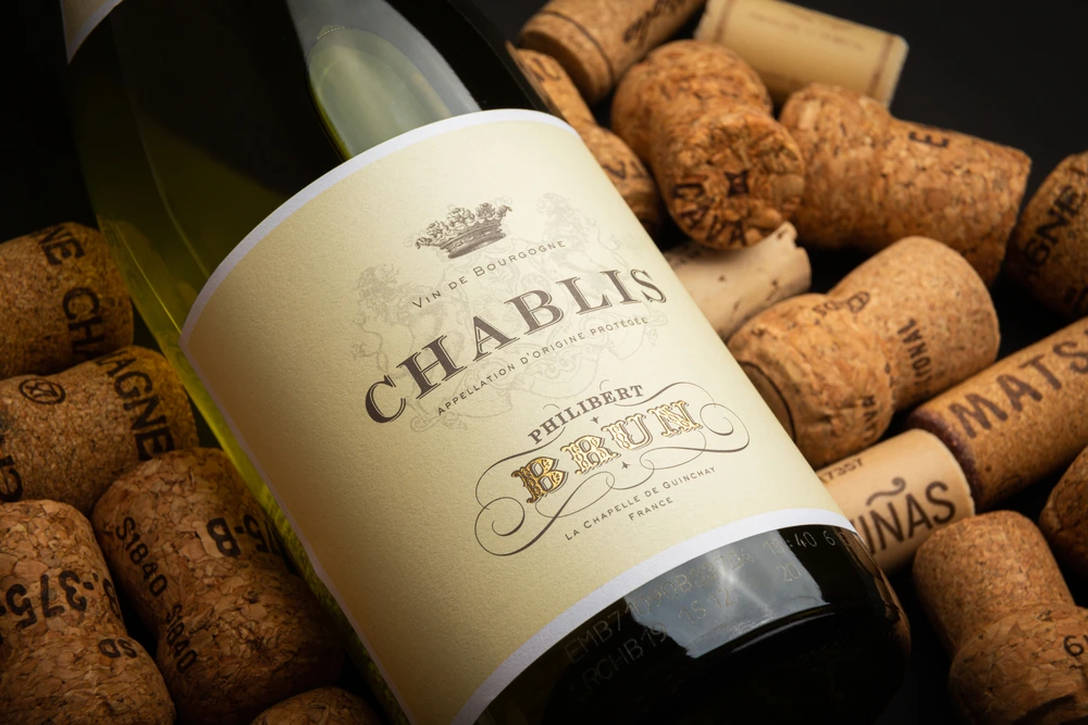 Chablis bottle among wine corks label close-up