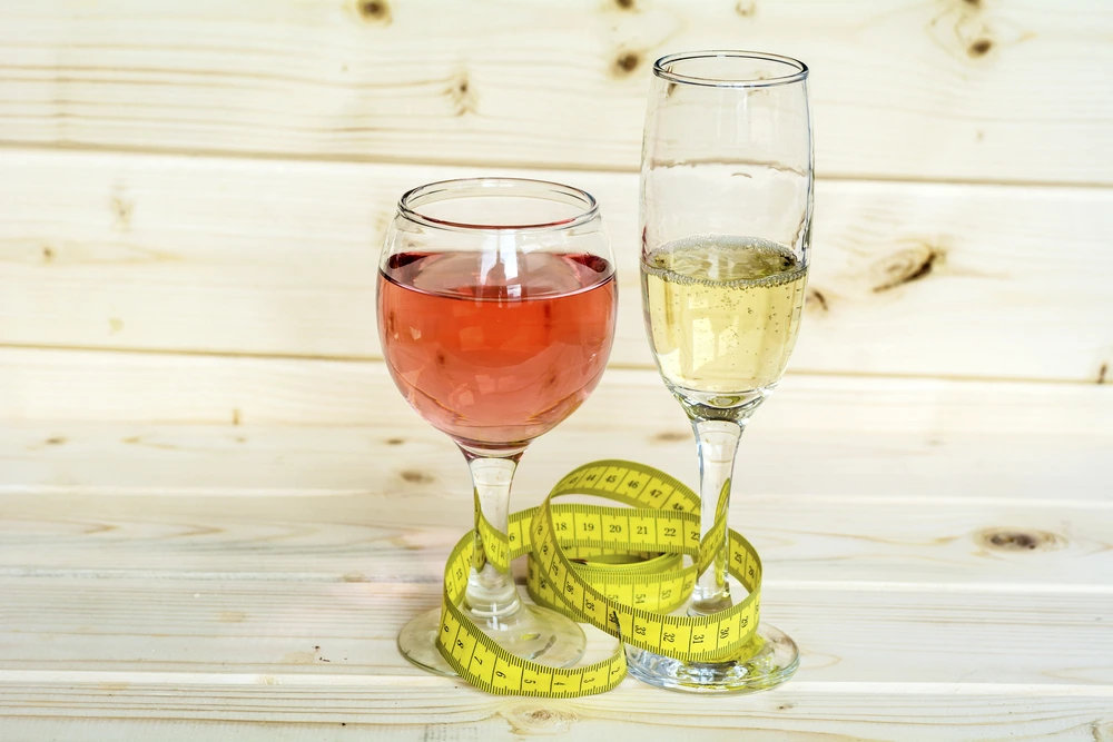 Glasses of wine and champagne with measuring tape on wooden background