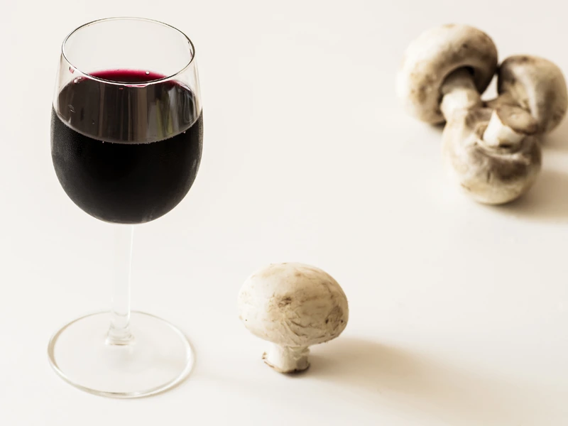 Glass of chilled red wine with mushrooms on white background