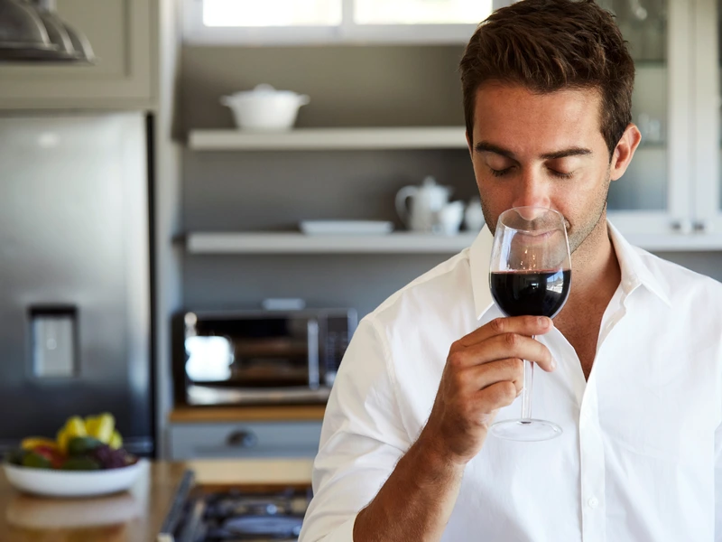 Man smelling red wine in a kitchen