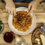 Plate of traditional spaghetti bolognese and glass of red wine on a wooden table