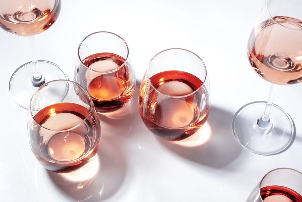 Rose wine of different shades in glasses on white background