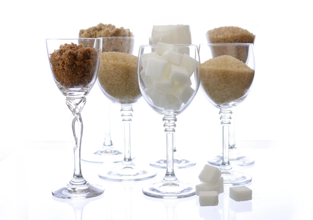 Glasses of wine filled with different kinds of sugar on white background