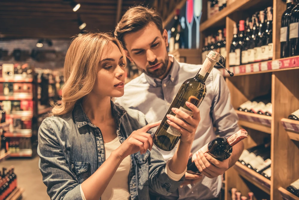 Attractive couple choosing which white wine to buy in a store
