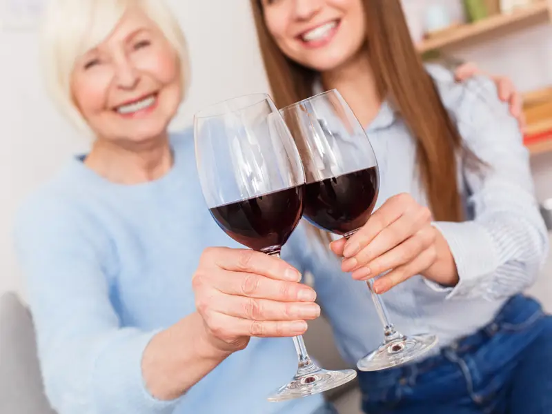 Two Women cheersing to health with red wine