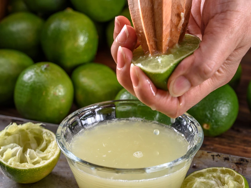 Fresh limes being hand-juiced into a bowl