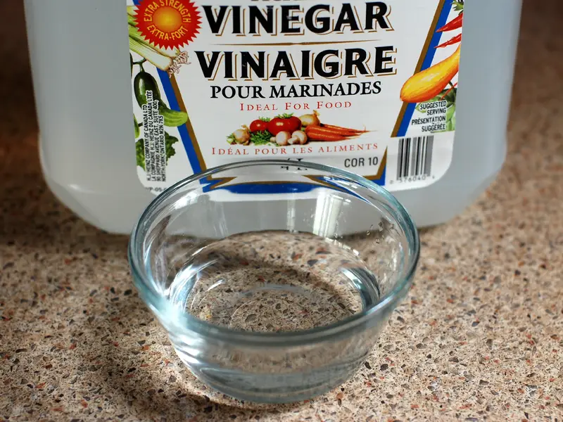 Branded white vinegar bottle with a clear cup of white vinegar
