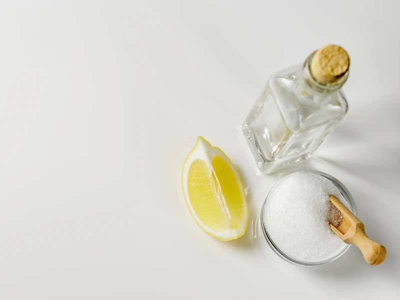 White vinegar with lemon and sugar on a white background