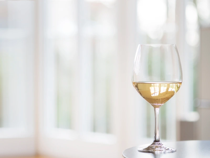 White wine glass sitting on a table off-focus background