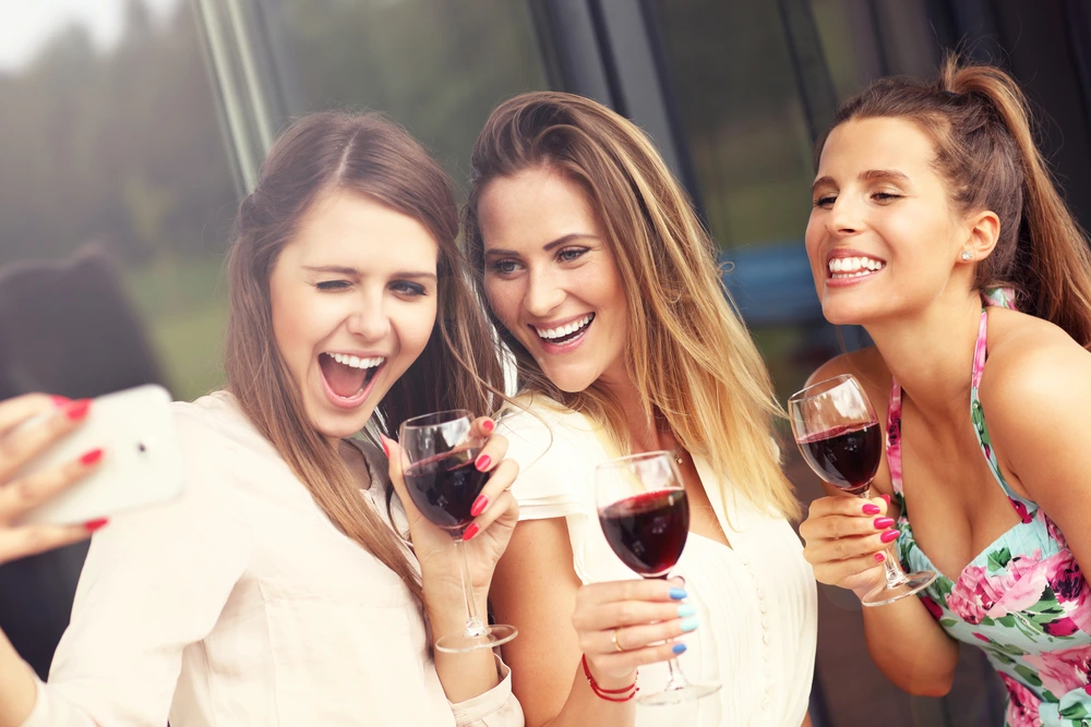 Three women taking selfies with wine for Instagram
