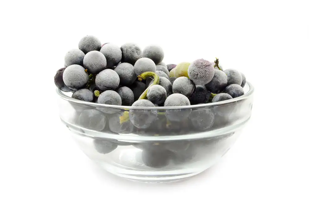 Frozen grapes in a bowl on a white background