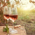 Two glasses of white zinfandel wine on a basket out in a vineyard