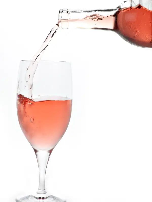 White Zinfandel being poured from a bottle into a glass white background