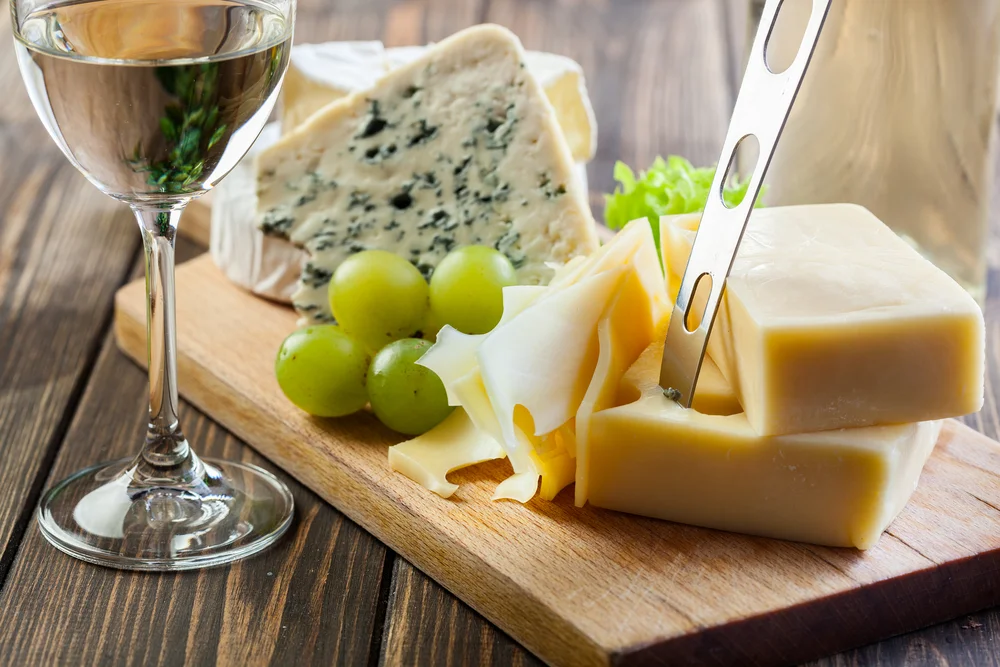 White wine with assorted cheeses on a serving platter close-up