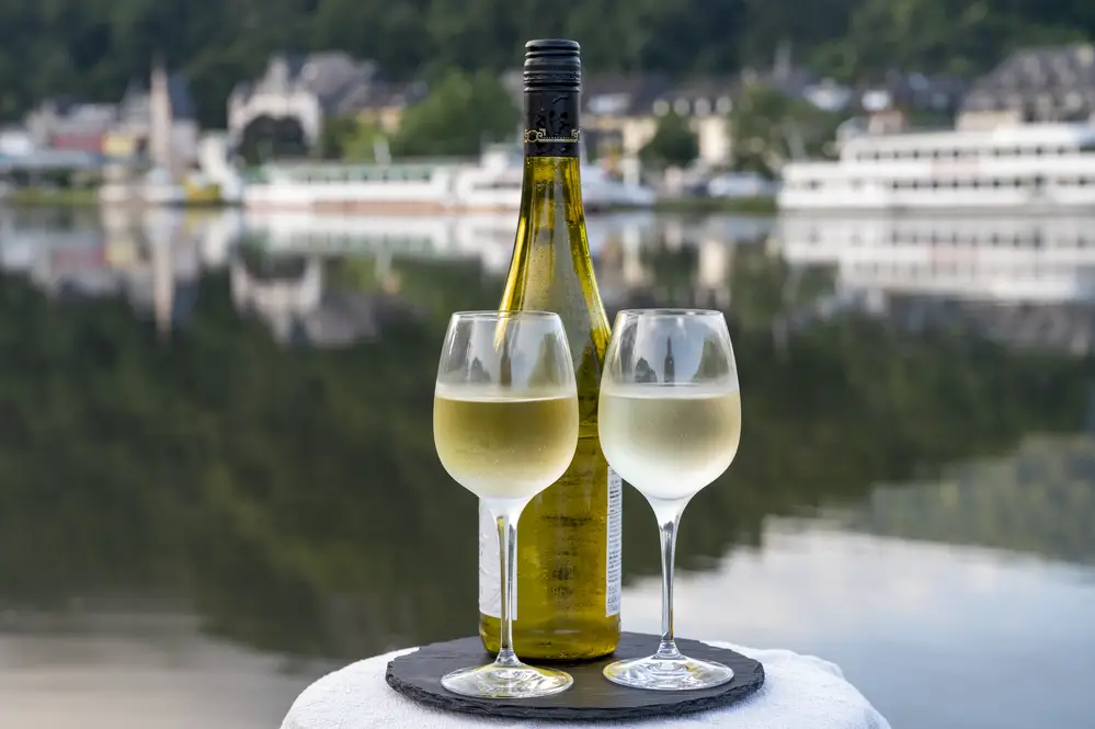 Bottle and glasses of Riesling on an outdoor patio beside a river in Germany